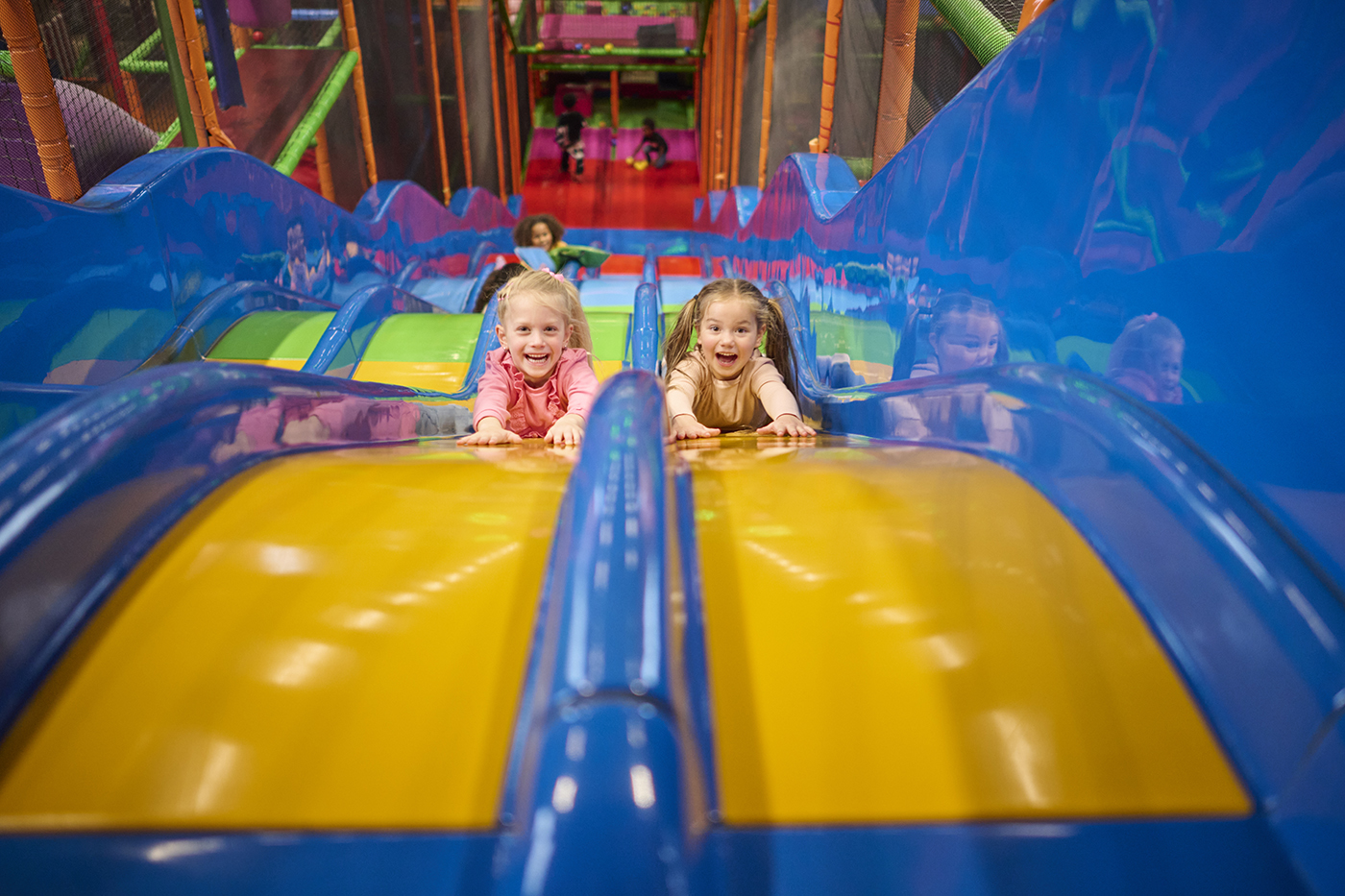 Happy children sliding backwards down a slide